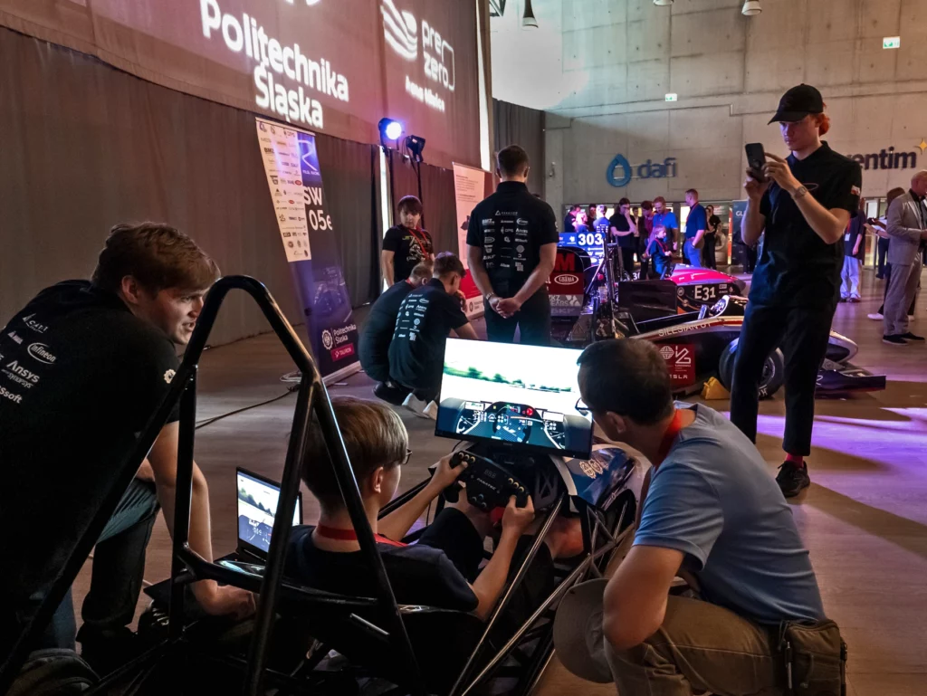 Uczestnicy wydarzenia oglądają bolidy zespołu PolSl Racing oraz symulator jazdy